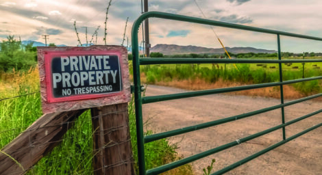 Panorama Security gate and fence with No Trespassing sign against mountain and cloudy sky. A&hellip;